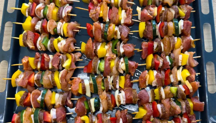 Szaszłyki w piekarniku: mięso, papryka, cebula i cukinia na patyczkach, gotowe do pieczenia.