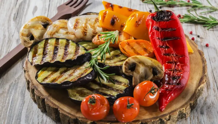Pyszne przekąski na grilla: grillowany bakłażan, papryka, pieczarki, pomidorki i cebula, udekorowane rozmarynem.