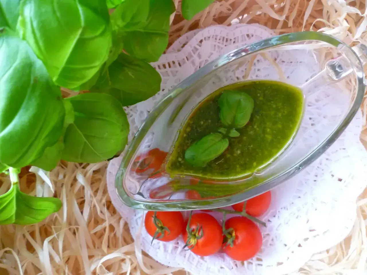 Aromatyczne pesto z bazylii w sosjerce, ozdobione listkami bazylii i pomidorkami koktajlowymi.