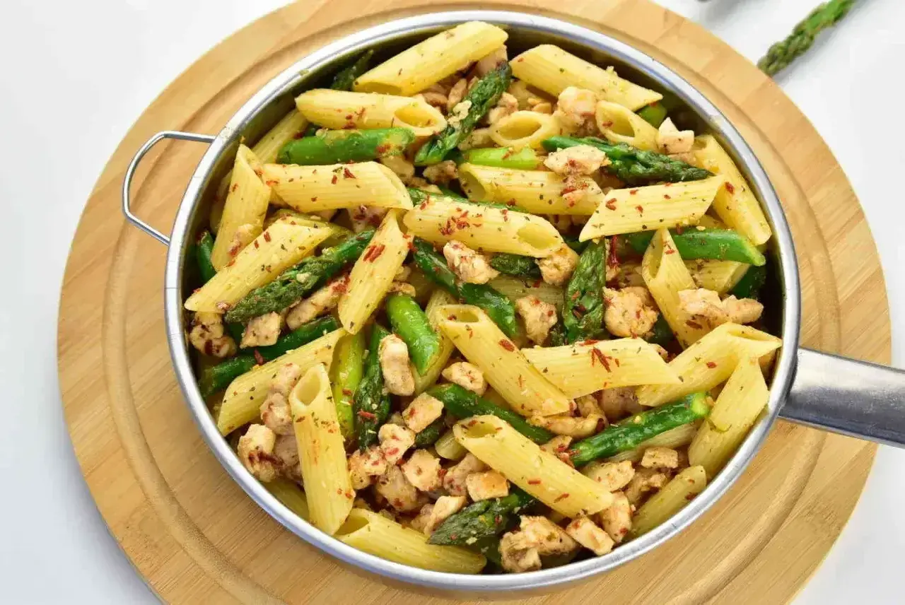 Penne z kurczakiem i szparagami, posypane papryką. Pyszne danie, które zachwyci każdego smakosza.