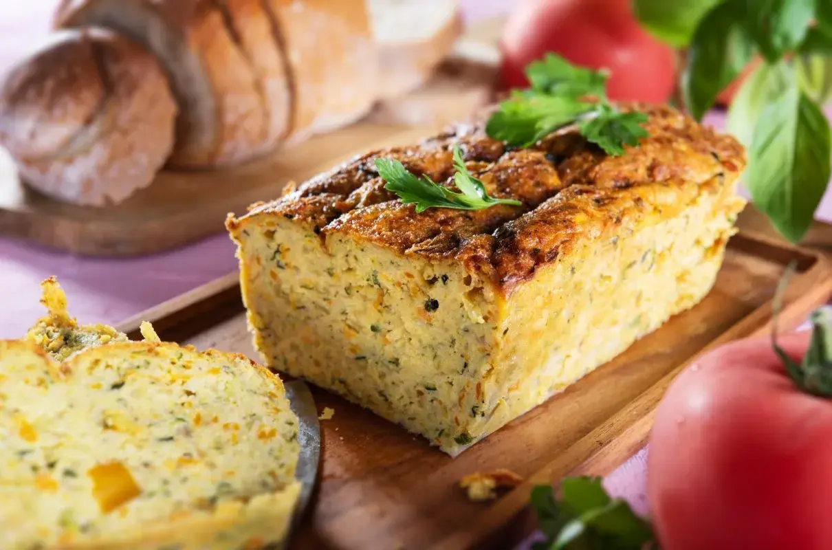 Pyszny pasztet z cukinii, lekki i aromatyczny, idealny na kanapki. Obok kromki chleba i pomidorów.