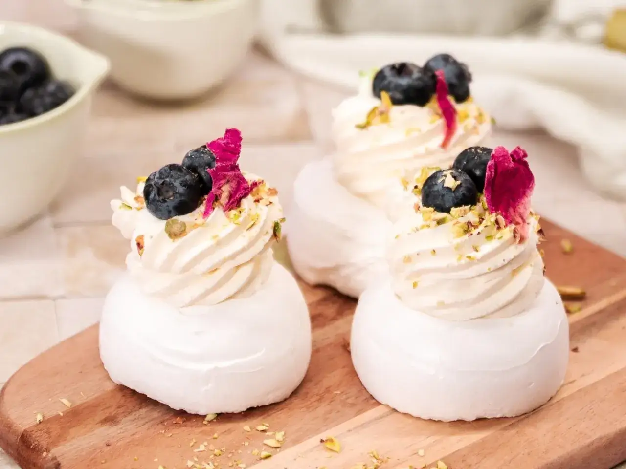 Mini pavlova z bitą śmietaną, borówkami i płatkami róży. Pyszna, lekka i idealna na deser.