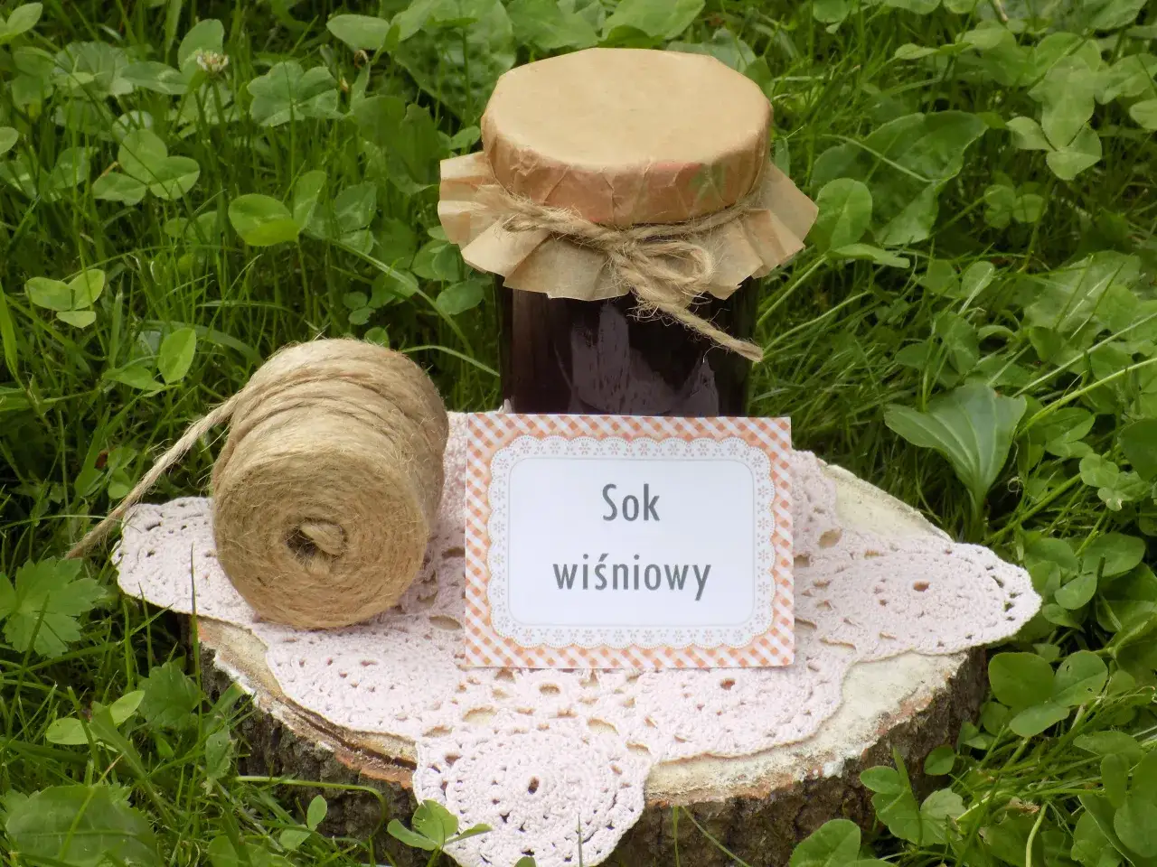 Sok z wiśni bez drylowania w słoiku, obok kłębka sznurka. Naturalny, domowy smak.