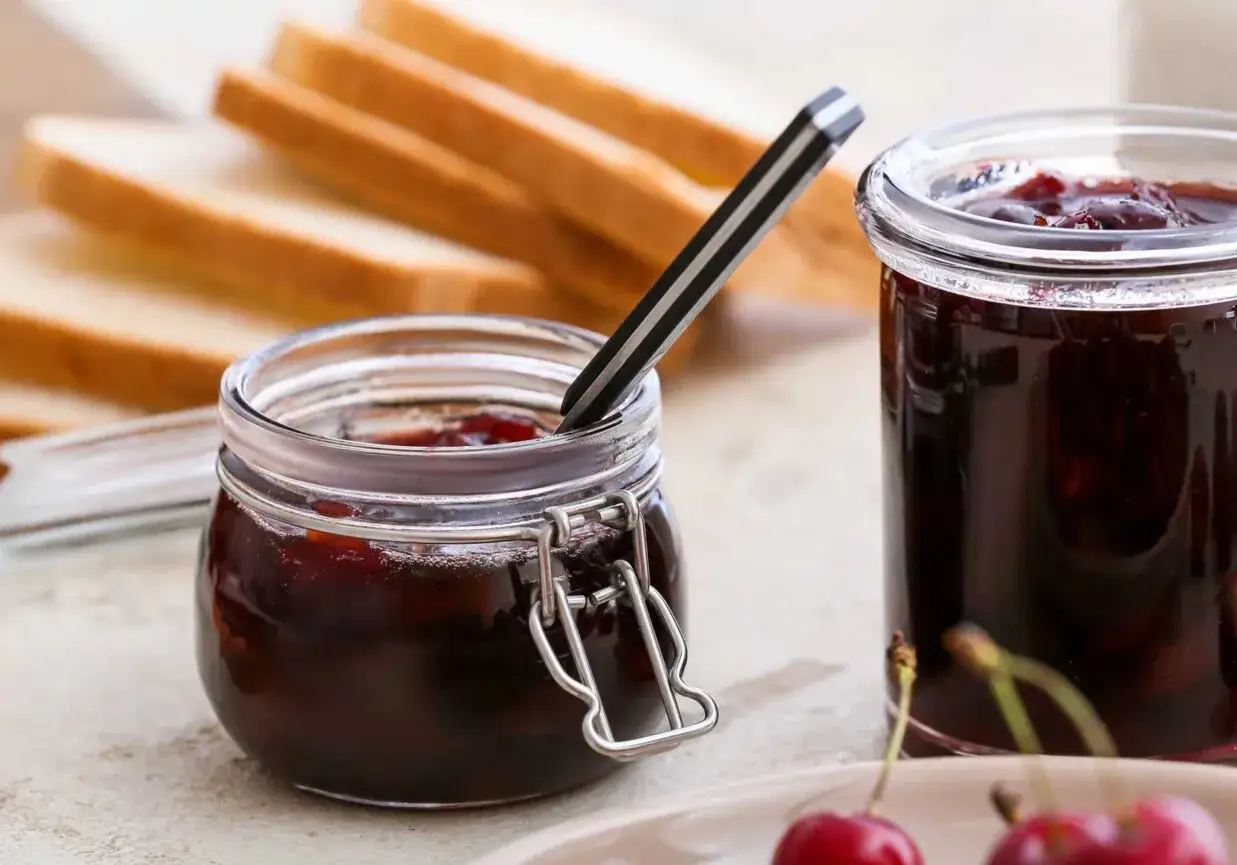 Słoiczki z domowym dżemem z wiśni, gotowe do rozsmarowania na tostach. Idealny dodatek do śniadania.